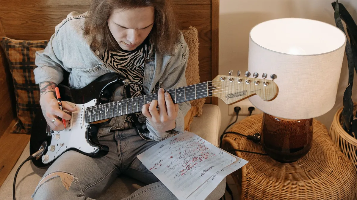 Guitarrista estudando com anota&ccedil;&otilde;es e tablaturas sobre a mesa