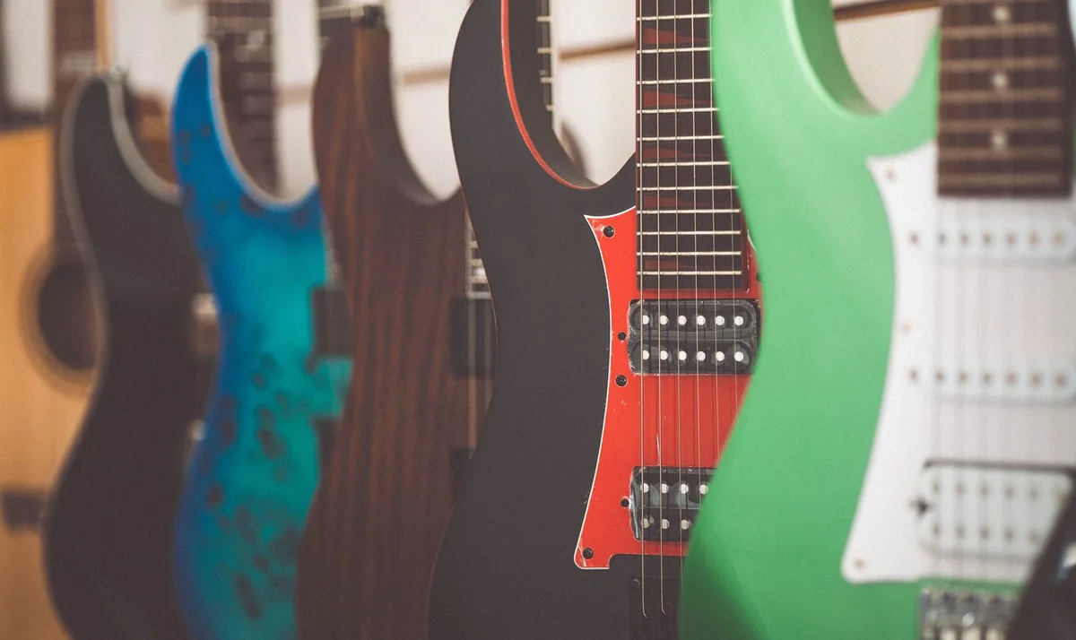 Top 10 guitarras para iniciantes 2026 — fileira de guitarras elétricas de cores diferentes, enfileiradas na parede de uma loja
