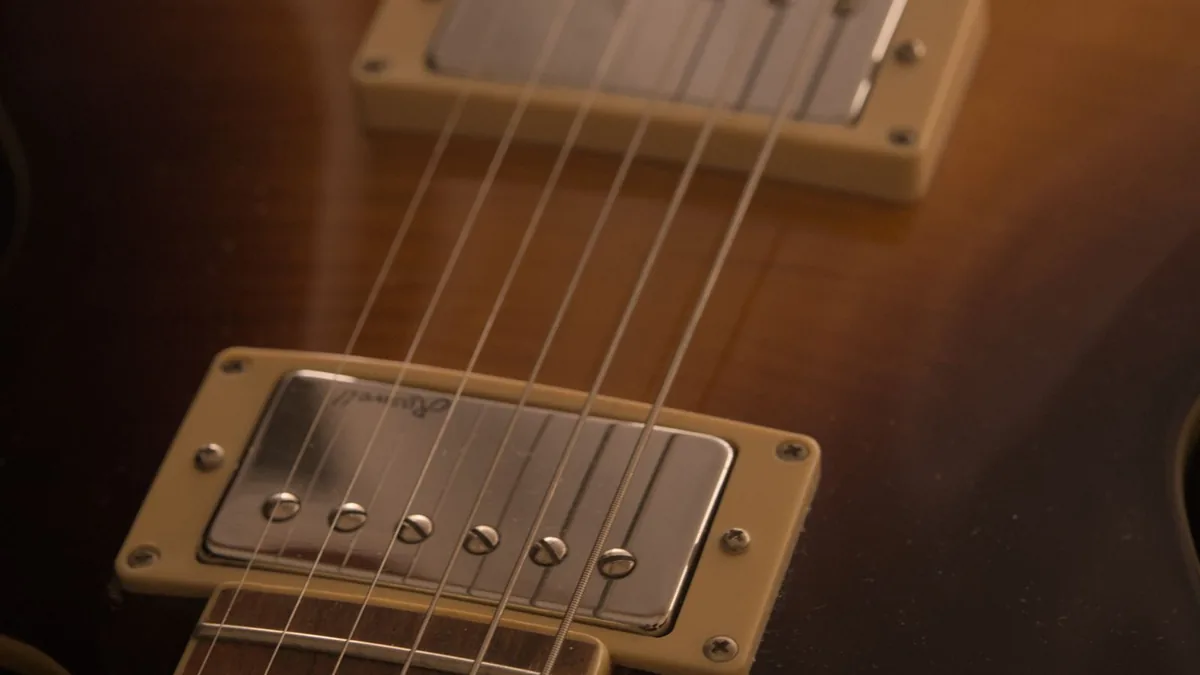 close nos dois captadores humbucker de uma guitarra Les Paul sunburst, com as cordas em primeiro plano