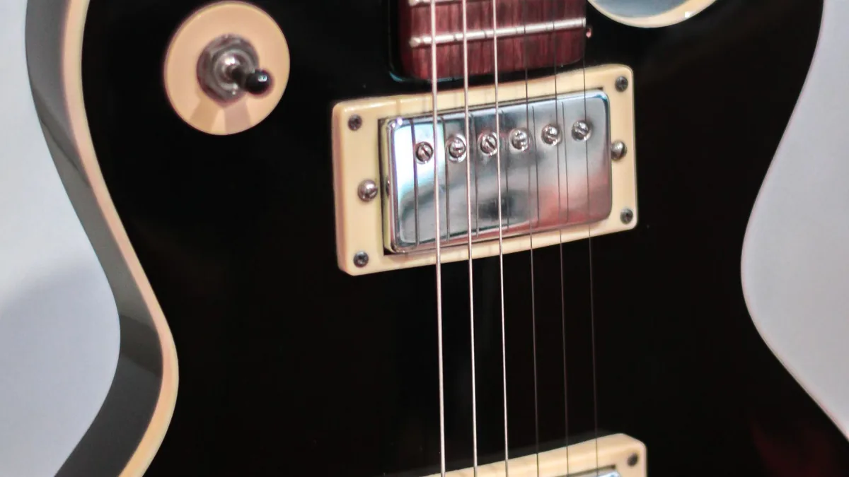 ponte de guitarra elétrica vista de perto, com cordas presas nos selins